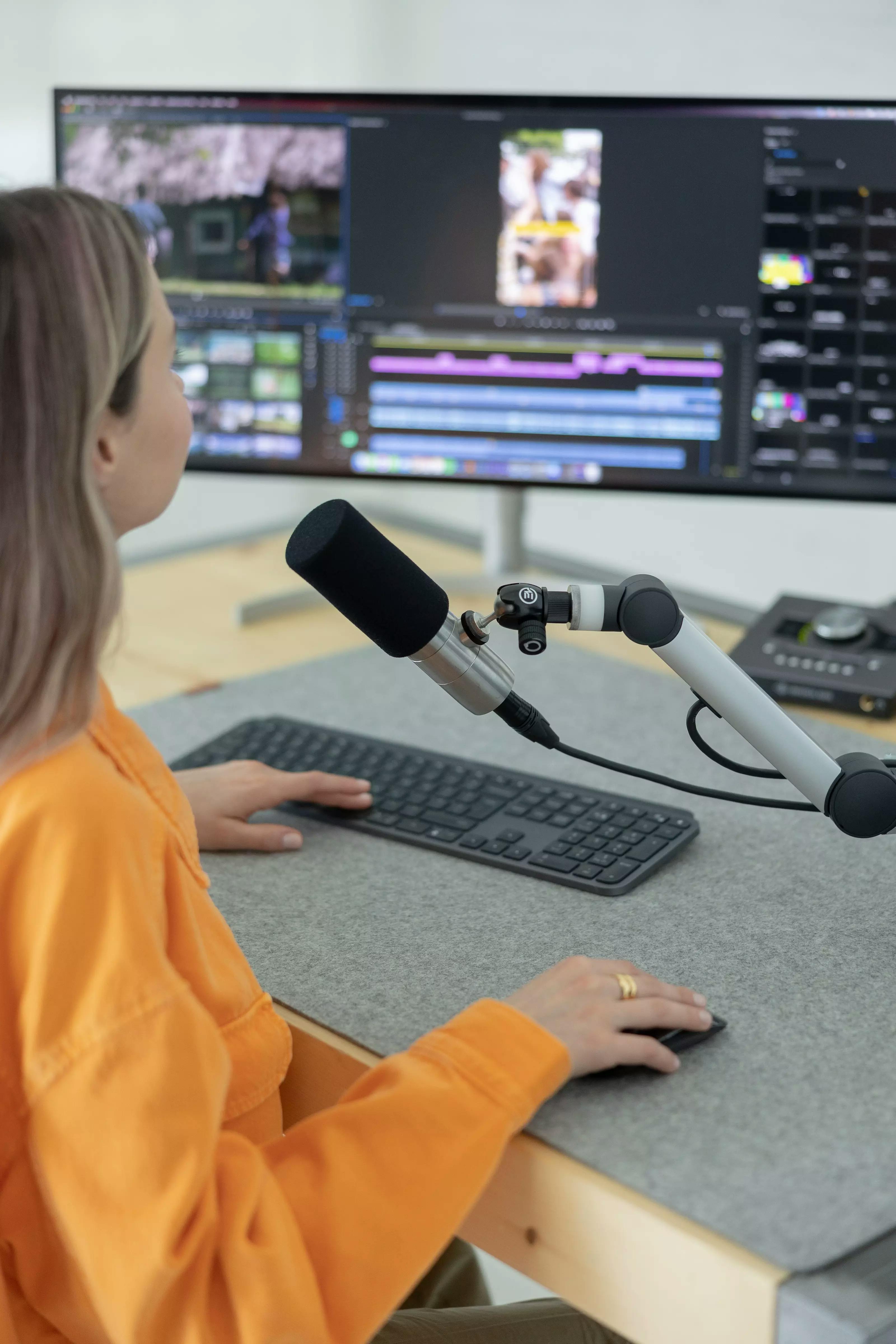 Stock photo of a woman recording a podcast, with a prominent microphone